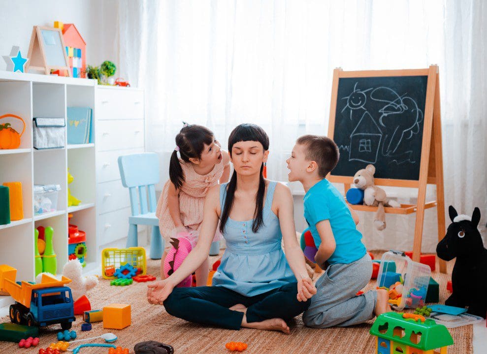 Mother meditating while her children play.