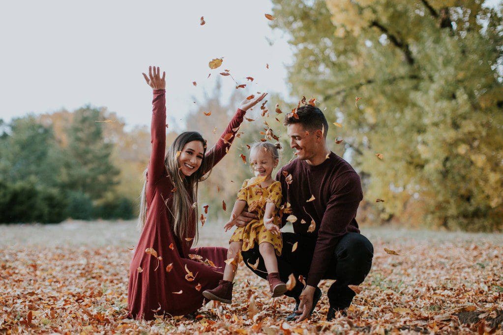 Family playing in fall leaves
