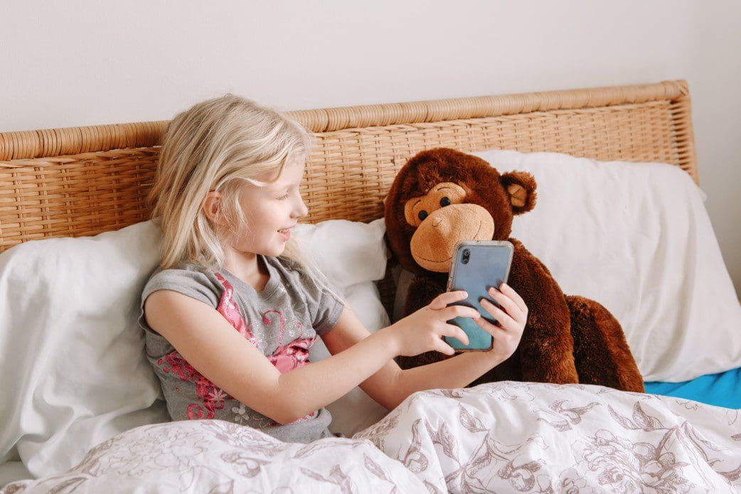 Child showing smartphone to stuffed animal