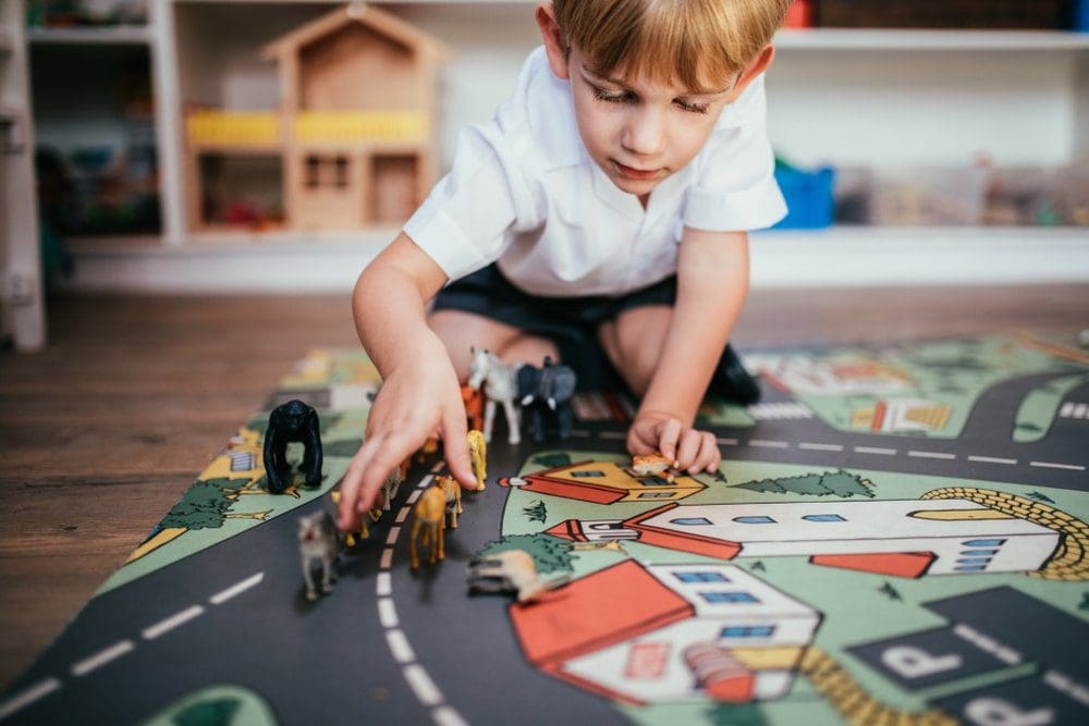 Child playing with a train on a carpet.