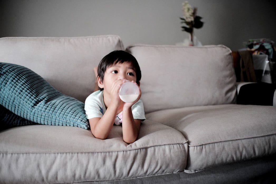 Child drinks milk on a couch during CBT therapy.