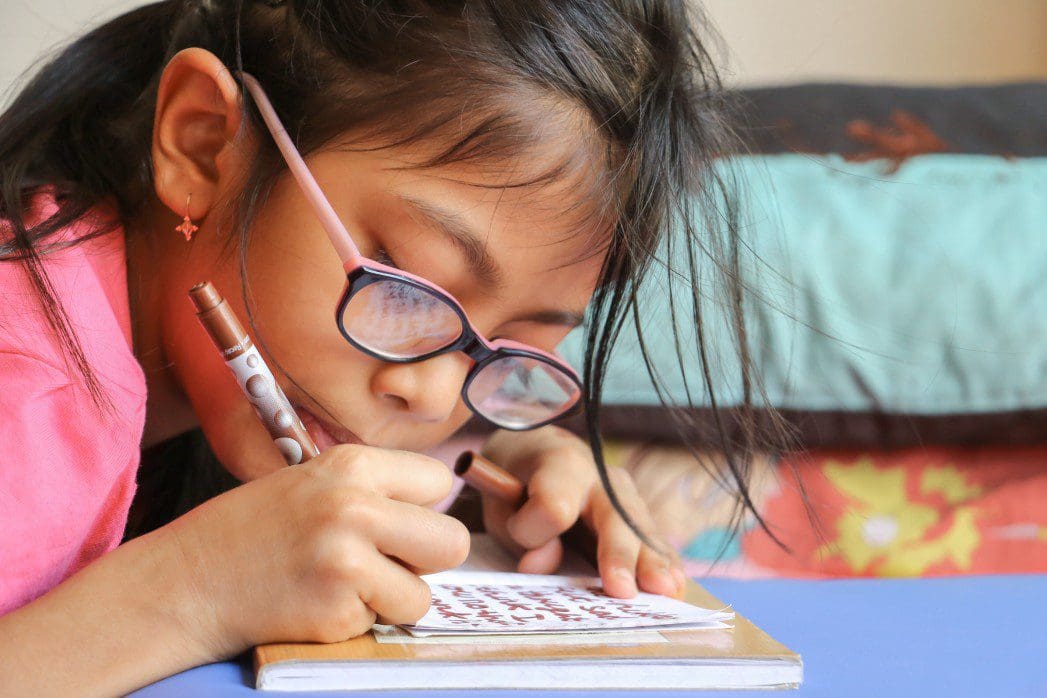 Child works on her fine motor skills by writing on a notepad.