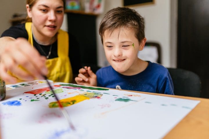 Young female art teacher working with autistic child
