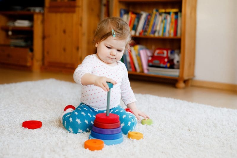 Adorable baby girl playing with a toy on the floor