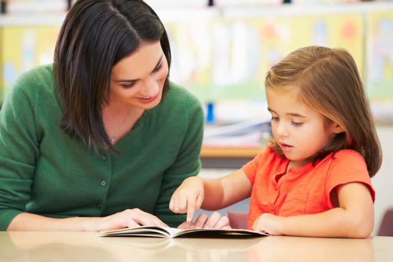 Teacher and young child reading a book